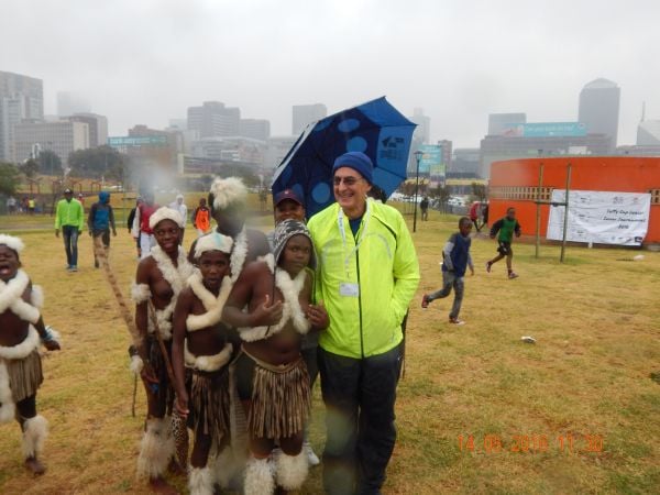 Photo of a man standing with children in the rain.